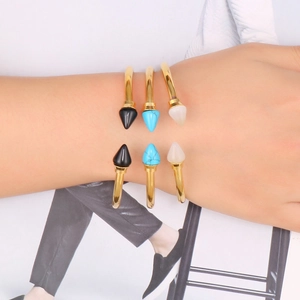Close-up of gold stainless steel bangle set with turquoise and black spiked cone studs