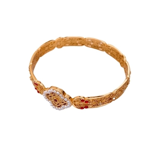 Vintage gold hollow filigree bangle with white pearls and red gemstones on white background