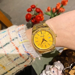 Detail of gold steel watch with yellow dial and date window on a female wrist
