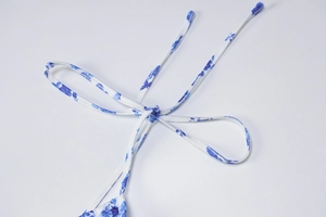 Detailed view of the blue floral print dress featuring an elegant white ribbon bow tie