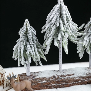 Miniature snow-covered Christmas tree trio on a natural wooden base for table decoration