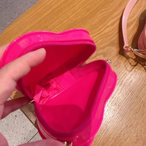 Detail view of pink heart-shaped jelly bag interior with zipper and strap on wood