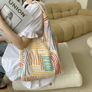 Close-up of colorful striped corduroy tote bag with Sazakka brand label in home setting
