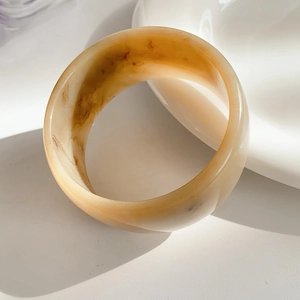 Macro shot of wide amber resin bangle with marble texture and polished finish