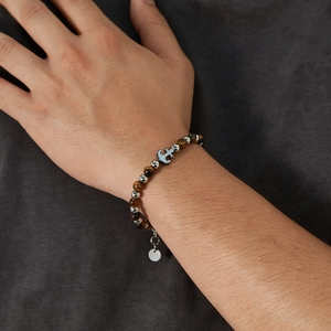 Men's tiger eye beaded bracelet featuring a silver anchor charm on a model's wrist