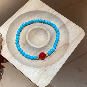Détail macro du bracelet en perles de turquoise avec agate rouge et accents dorés