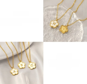 Macro detail of 18K gold-plated titanium steel clover necklace with shell alphabet pendant