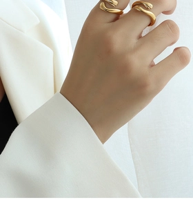 Close-up of dual gold hugging hands rings worn together on fingers for a layered look