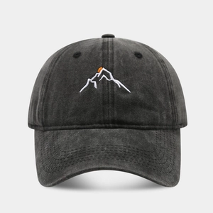 Macro detail of mountain embroidery on washed cotton baseball cap with orange sun accent