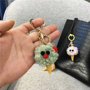 Close-up detail of a green plush ice cream cone keychain being held as a cute bag pendant.