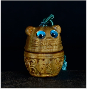 Macro shot of hand-carved sandalwood tiger pendant with blue inset eyes and wood grain