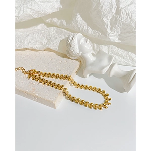 Detailed view of a gold wheat leaf chain bracelet with adjustable lobster clasp on marble