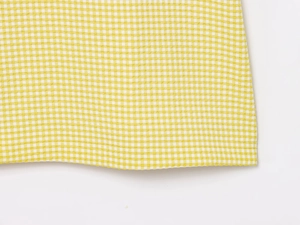 Close-up of yellow and white gingham fabric with premium flat stitched hem detail