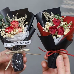 Close-up of mini dried rose bouquets with Best Wishes ribbon in black wrapping paper
