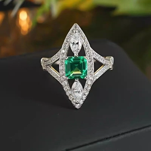 Macro detail of vintage emerald cut green gem and marquise stones on textured silver ring