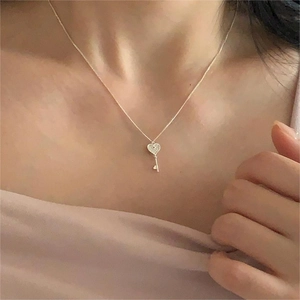 Detail shot of a silver heart key pendant necklace worn on the collarbone for a chic look