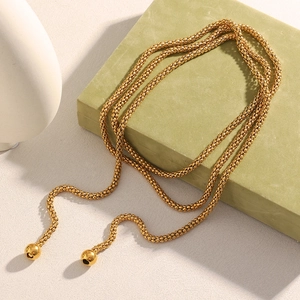 Detail of 18K gold-plated popcorn chain necklace with spherical pendants on green pedestal
