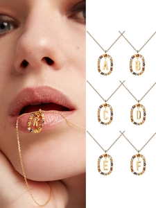 Detailed view of gold chain necklaces featuring colorful crystal-encrusted letter pendants