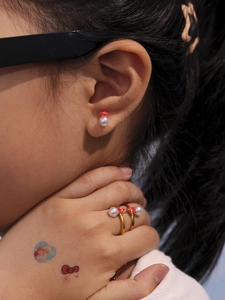 Detalle de pendientes y anillos de estrella roja sonriente con perlas doradas