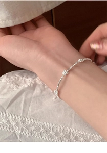 Dettaglio del bracciale a farfalla in argento S925 indossato su pizzo bianco fine