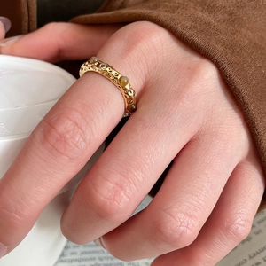 Close-up of gold-plated tiger eye ring with hammered texture on a hand holding a cup