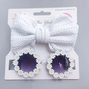 Macro view of white daisy floral sunglasses and waffle bow headband set for toddlers