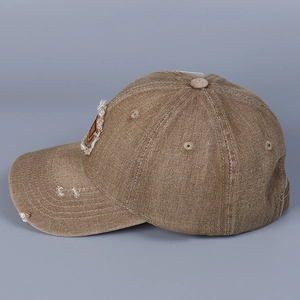 Dettaglio del cappellino in denim lavato con bordi vintage consumati e toppa con lettera D
