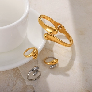 Close-up of minimalist gold and silver drop-shaped bangles and rings on ceramic