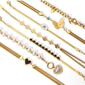 Detail of gold-plated chain bracelets featuring pearls, evil eye, and heart charms