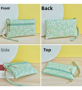 Detail view of small green floral pouch with dual zippers and matching wrist strap
