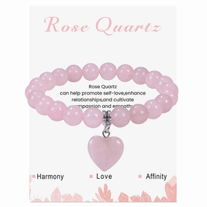 Gros plan d'un bracelet en perles de quartz rose avec pendentif coeur sur carte