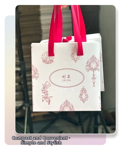 Vue détaillée d'un sac cadeau en papier blanc avec motifs vintage rouges et rubans satin