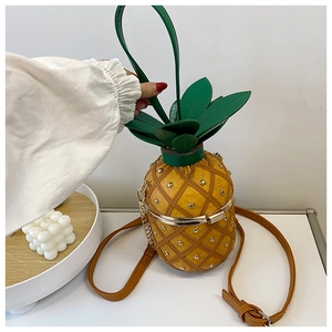 Detailed macro view of yellow pineapple bag with golden studs and green leather leaves