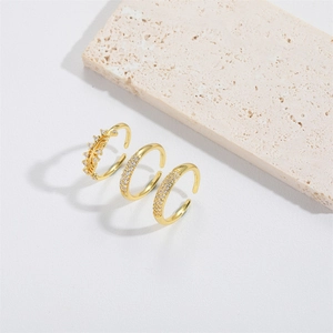 Minimalist gold teardrop open rings set with clear crystals on a stone background