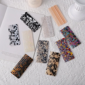 Close-up of tortoise shell and marble acetate wide-tooth hair combs on a lace fabric