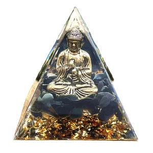 Orgone pyramid with golden Buddha statue and black obsidian stones on white background