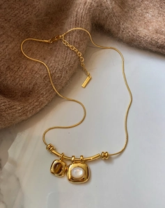 Détail du collier chaîne serpent plaqué or 18K avec pendentifs oeil de tigre et blanc