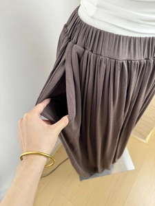 Detailed view of elastic waist and side pockets on brown pleated irregular culottes