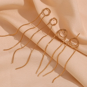 Detail view of gold snake chain tassel earrings on elegant light silk fabric