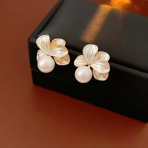 Détail macro de boucles d'oreilles fleurs et perles rétro français dorées sur écrin noir