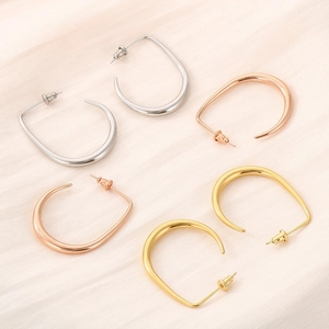 Macro detail of U-shaped minimalist earrings in gold, silver and rose gold steel
