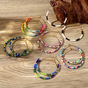 Detail of colorful bohemian beaded hoop earrings on a natural wood surface background