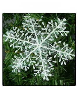 White plastic snowflake ornament with colorful tinsel detail on a green Christmas tree