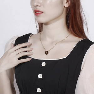 Golden stainless steel round necklace with letter E pendant worn by a female model