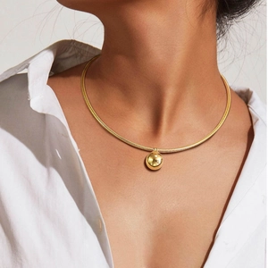 Close-up of a 18K gold-plated snake chain necklace with a smooth spherical pendant on a neck