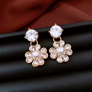 Dettaglio orecchini a fiore placcati oro 18K con perle bianche e zirconi su pelle nera