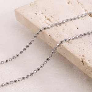 Close-up of a silver ball chain necklace laid on a textured stone for a vintage look