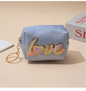 Close-up of blue sequin embroidered LOVE mini coin purse with golden keychain and zipper