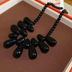Gros plan d'un collier de perles en acrylique noir avec pendentifs en forme de goutte d'eau