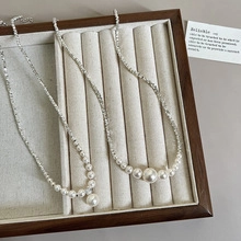Close-up of elegant gradient pearl necklace with shimmering silver chain on velvet tray